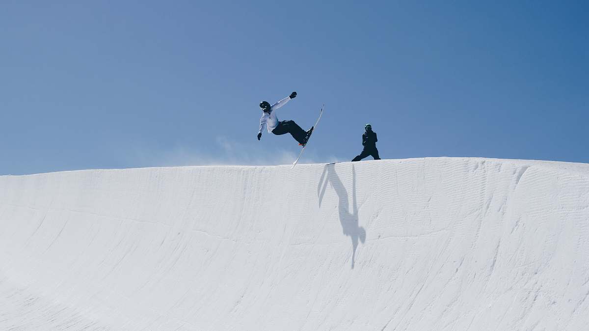 Capture the exhilarating moment of an outdoor enthusiast skillfully executing a trick on a snow ramp under the bright daylight. This vibrant scene showcases the adrenaline and excitement of snowboarding, making it perfect for adventure sports magazines, promotional materials for winter sports gear, or lifestyle blogs centered around snow activities. The glistening snow and dynamic movement create a visually stunning image that appeals to fans of winter sports and outdoor adventures.