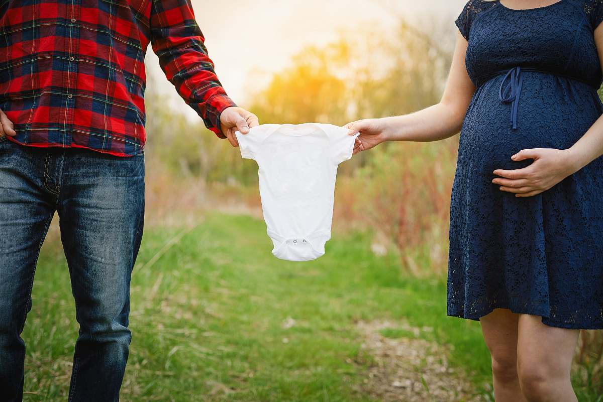human both man and woman holding baby's white onesie person