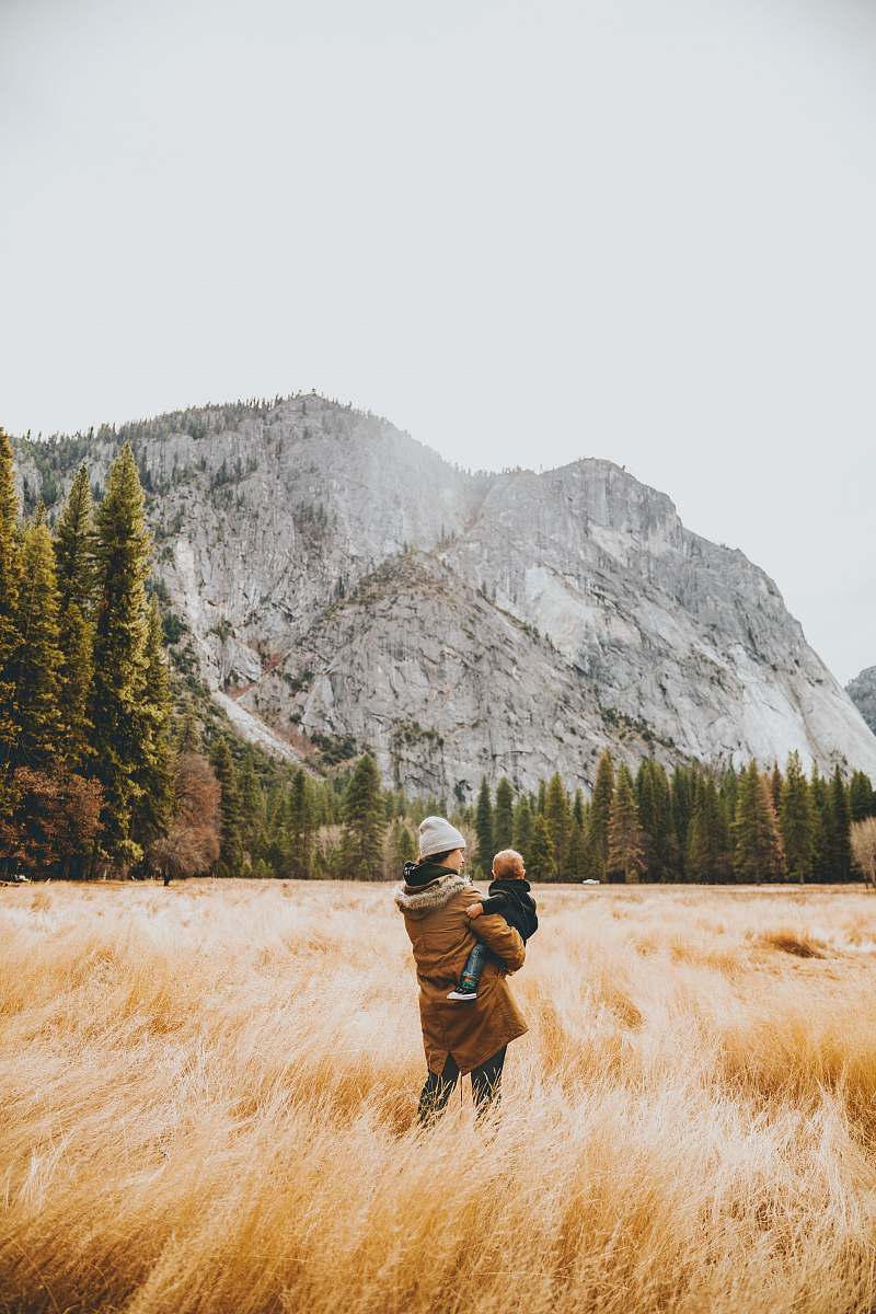 person person standing on grass field while carrying child human