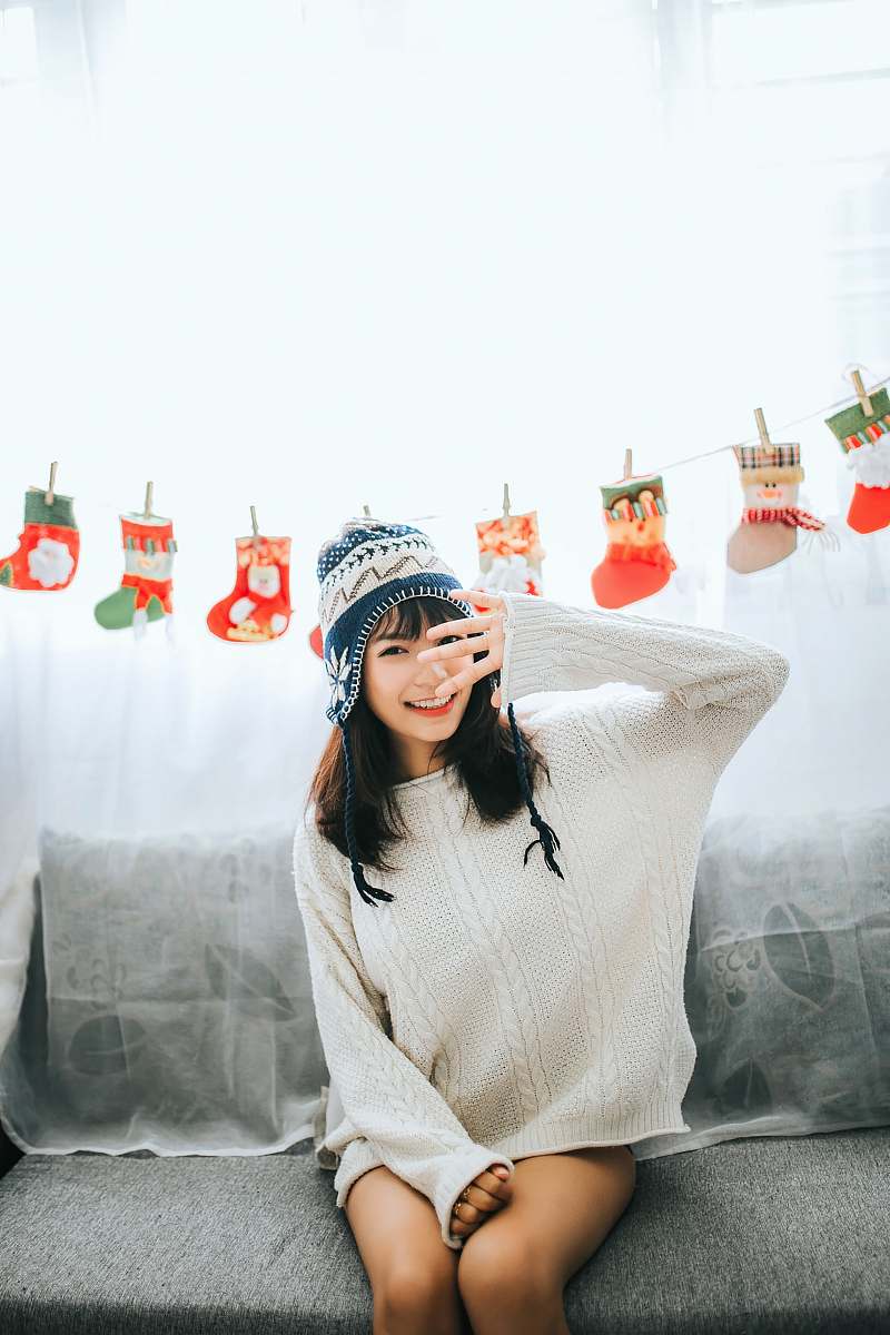 human woman wearing white sweater sits on gray fabric sofa person