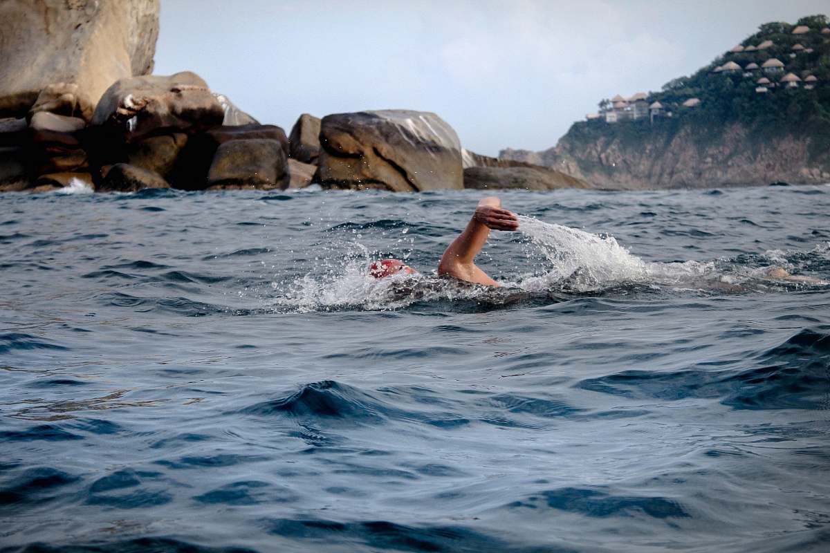human person swimming across brown rocks sport
