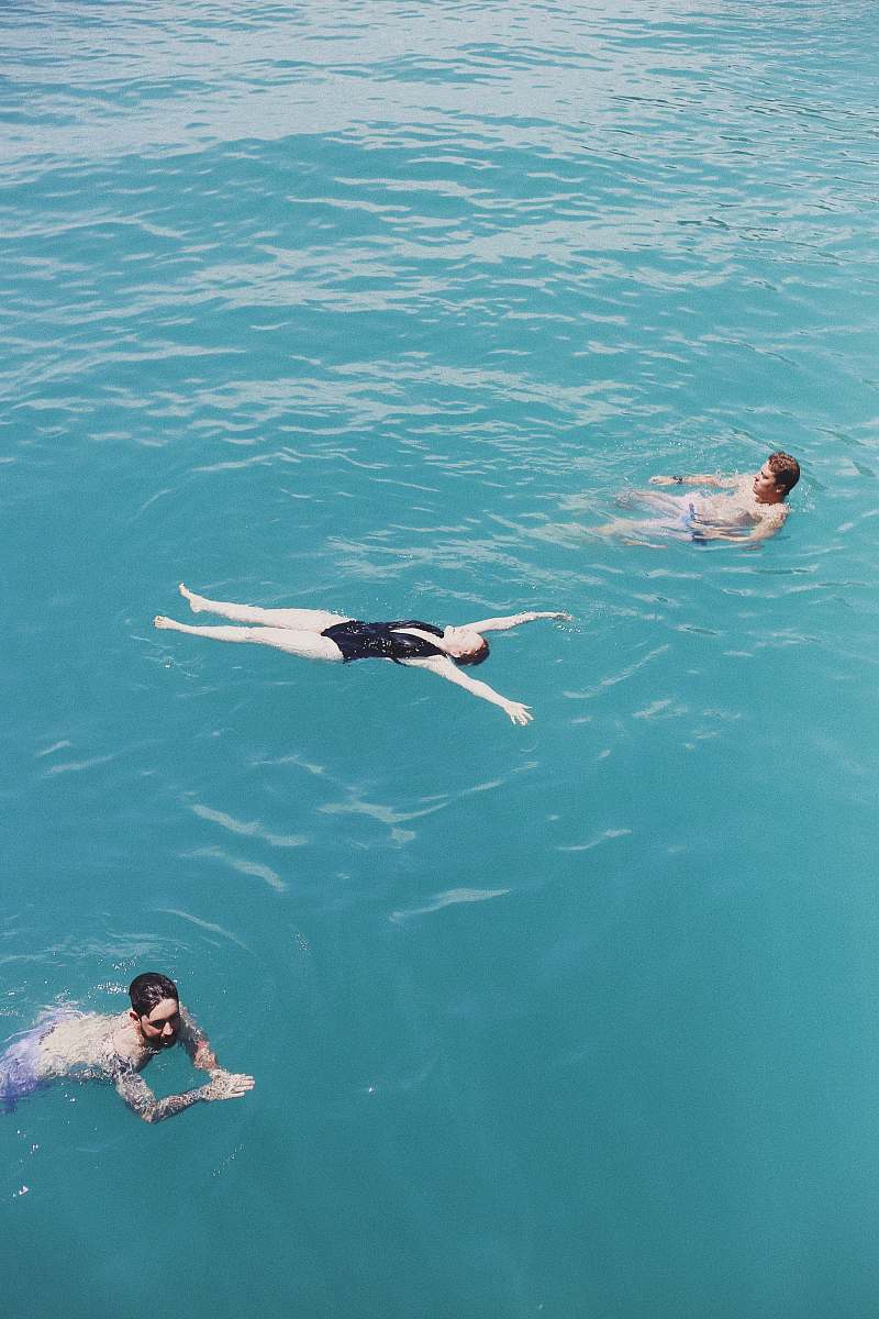water three people on body of water swimming