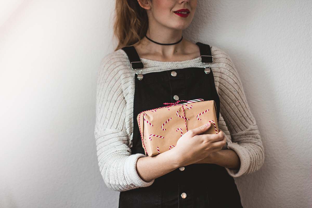 people woman carrying brown leather bag while standing near white painted wall human