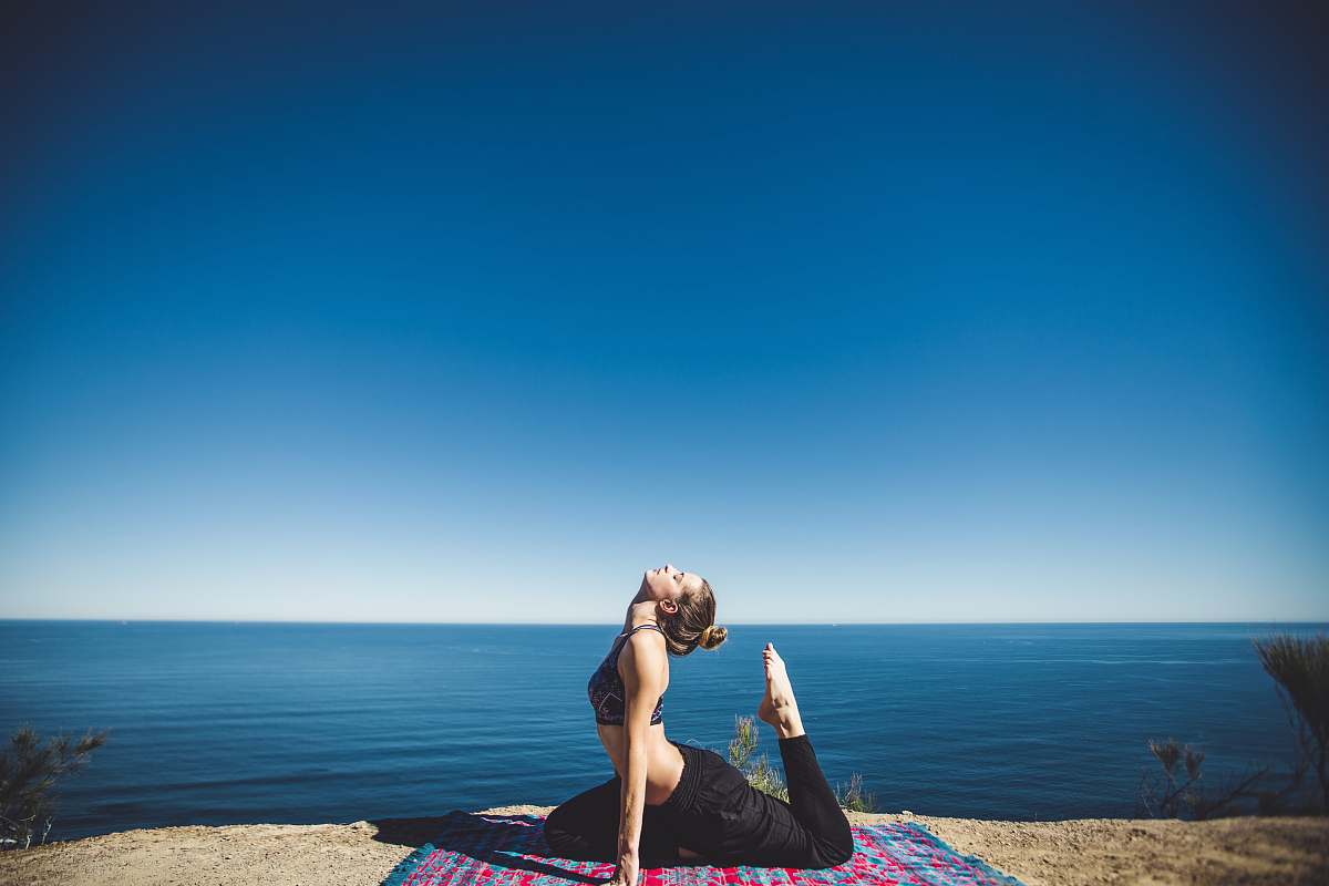 people woman wearing black top and pants stretching body on mat yoga