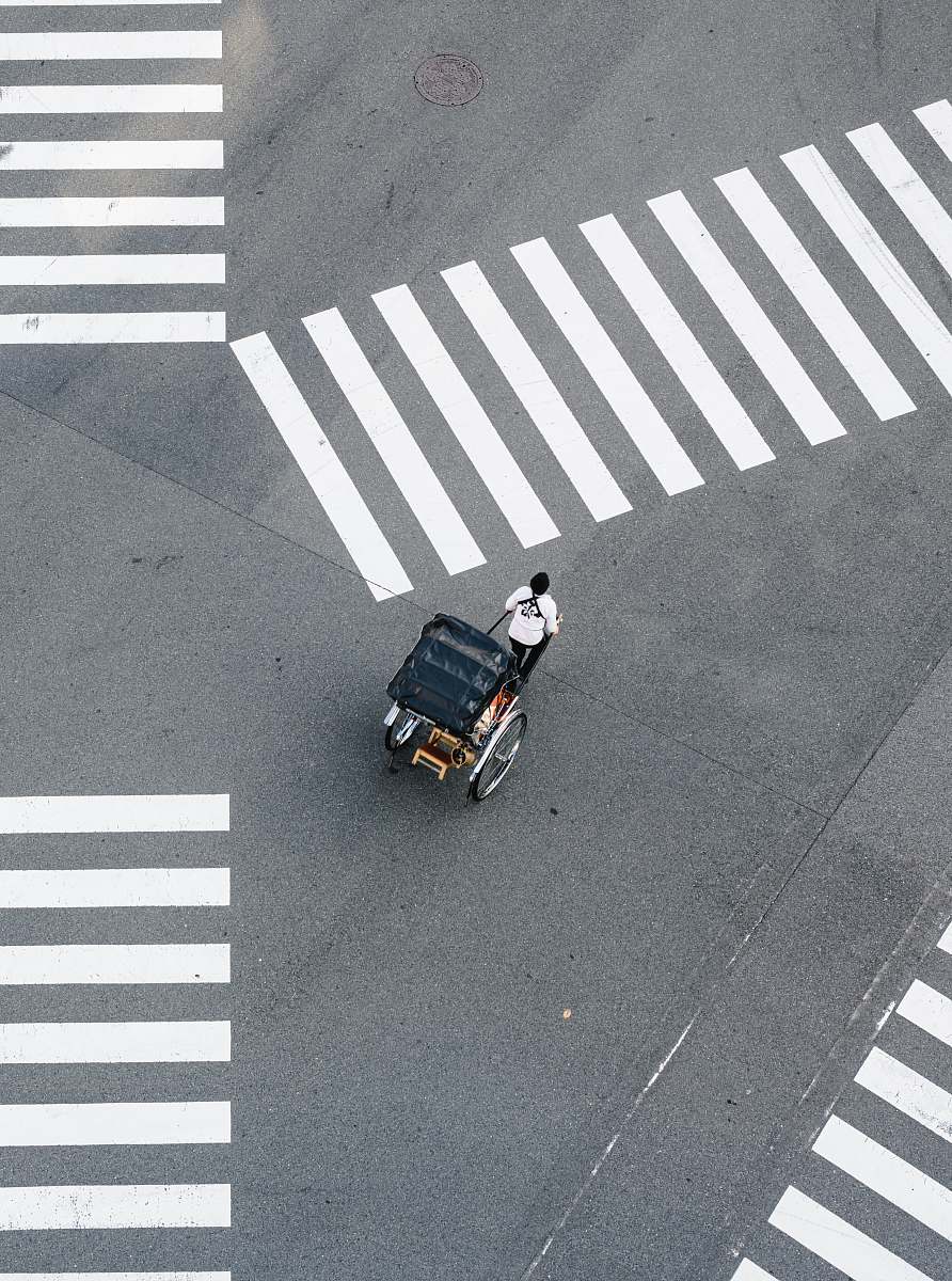 asphalt man pulling carriage crossing pedestrian tarmac