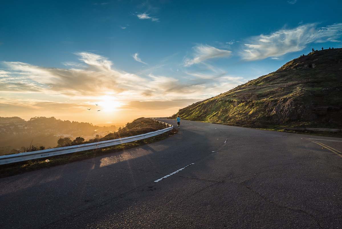 asphalt person running on road street cliff during golden hour sky