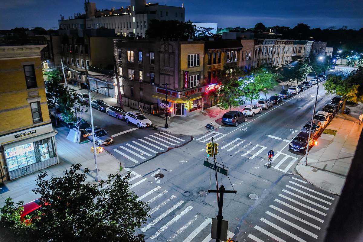 asphalt road crossing with cars near buildings during daytime with lights tarmac