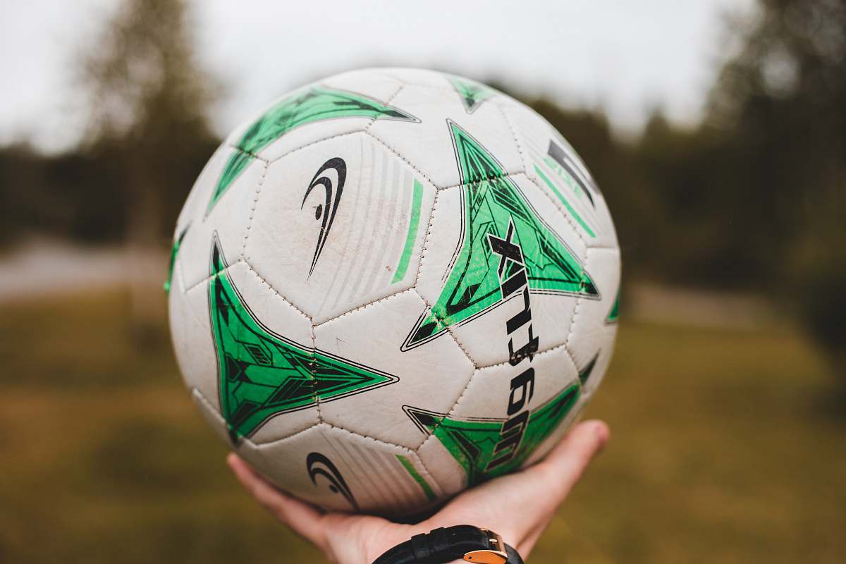 ball person holding white and multicolored soccer ball football