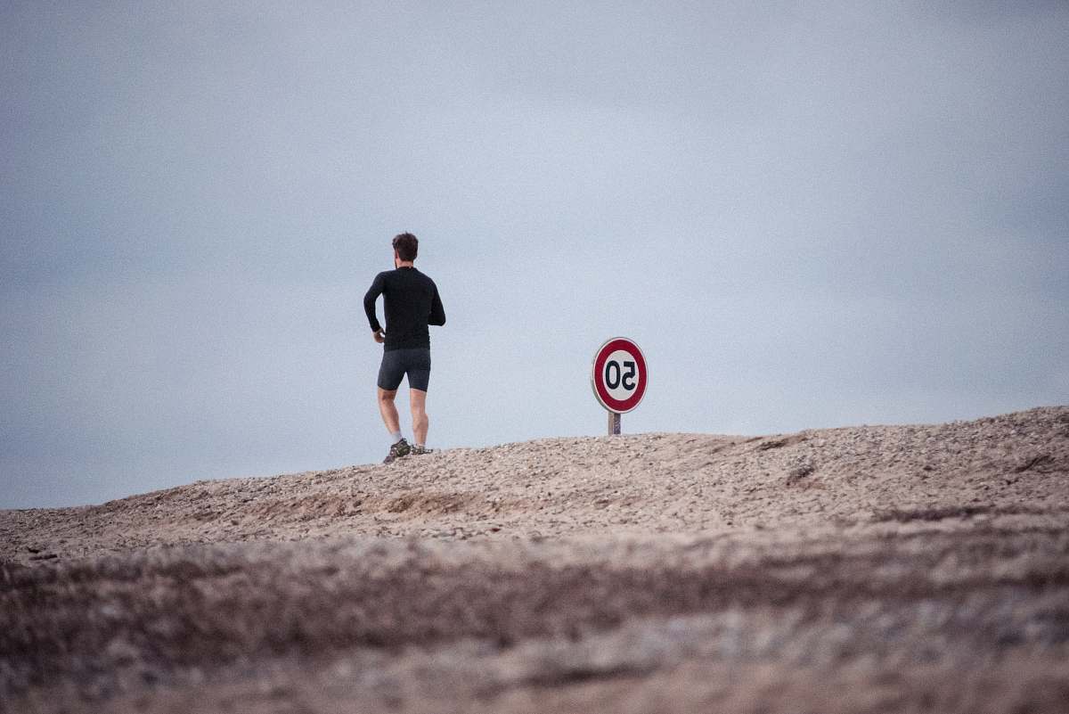 jogging man wearing black top standing near road signage during daytime people