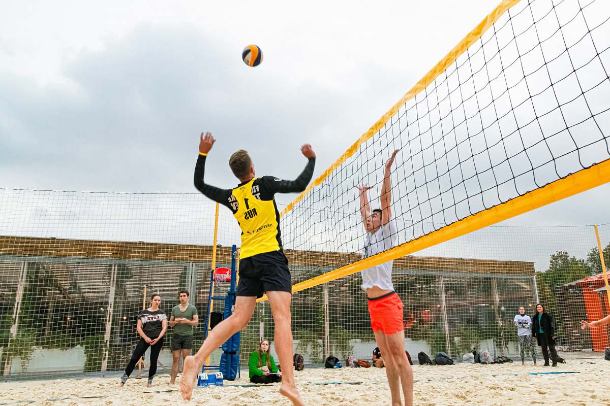 human man wearing yellow and black long-sleeved shirt playing volleyball team sport
