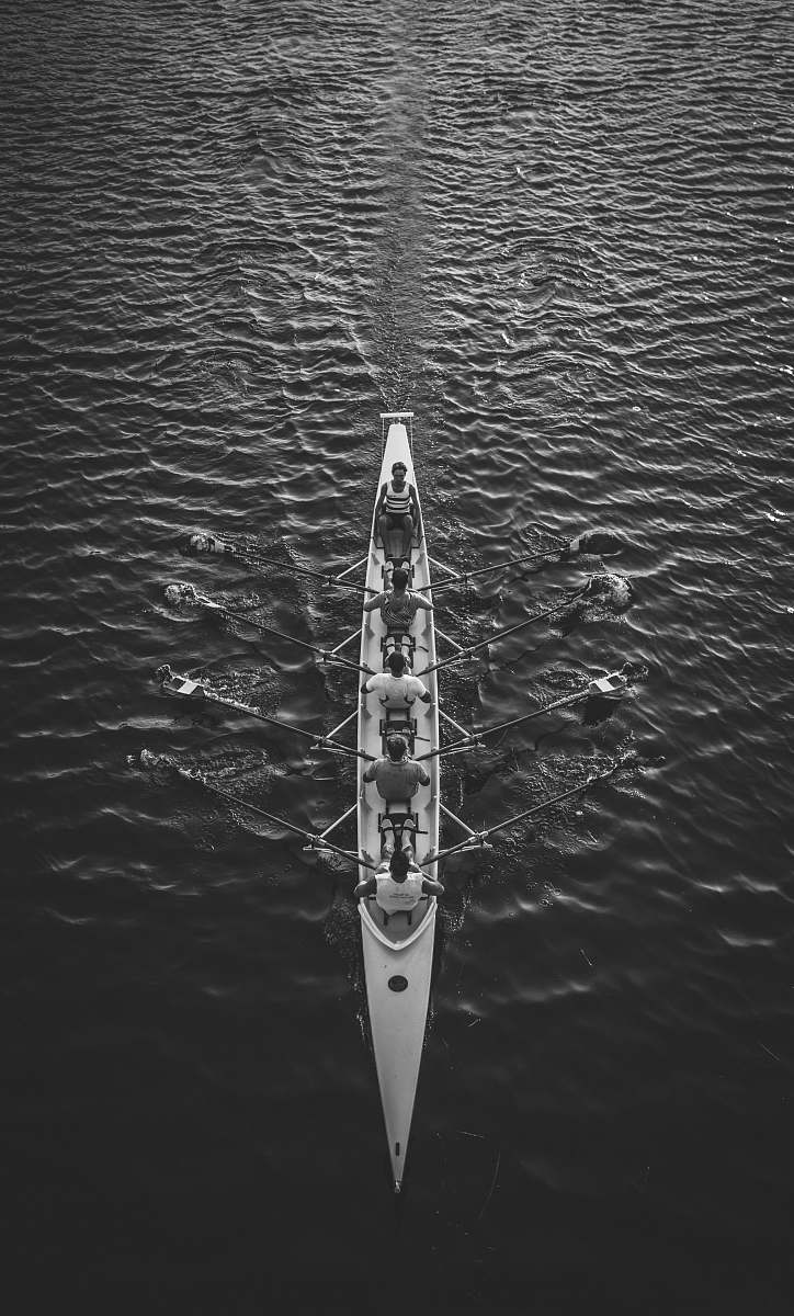 team people riding boat on body of water black-and-white