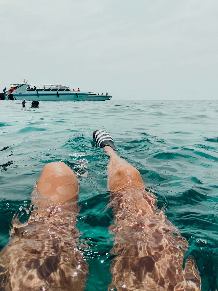 human person swims near yacht person