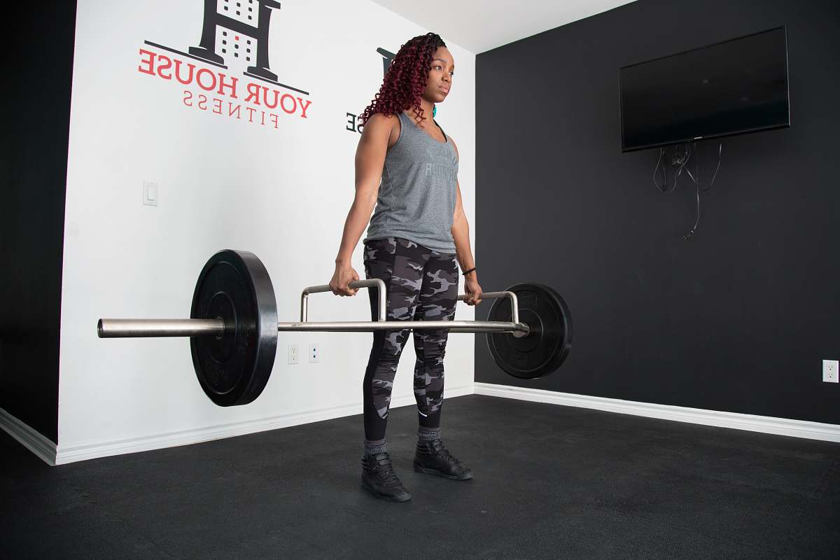 sports woman standing and lifting barbell working out