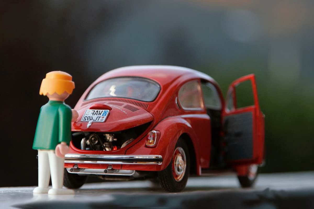 car orange hair Lego toy looking at red beetle car toys