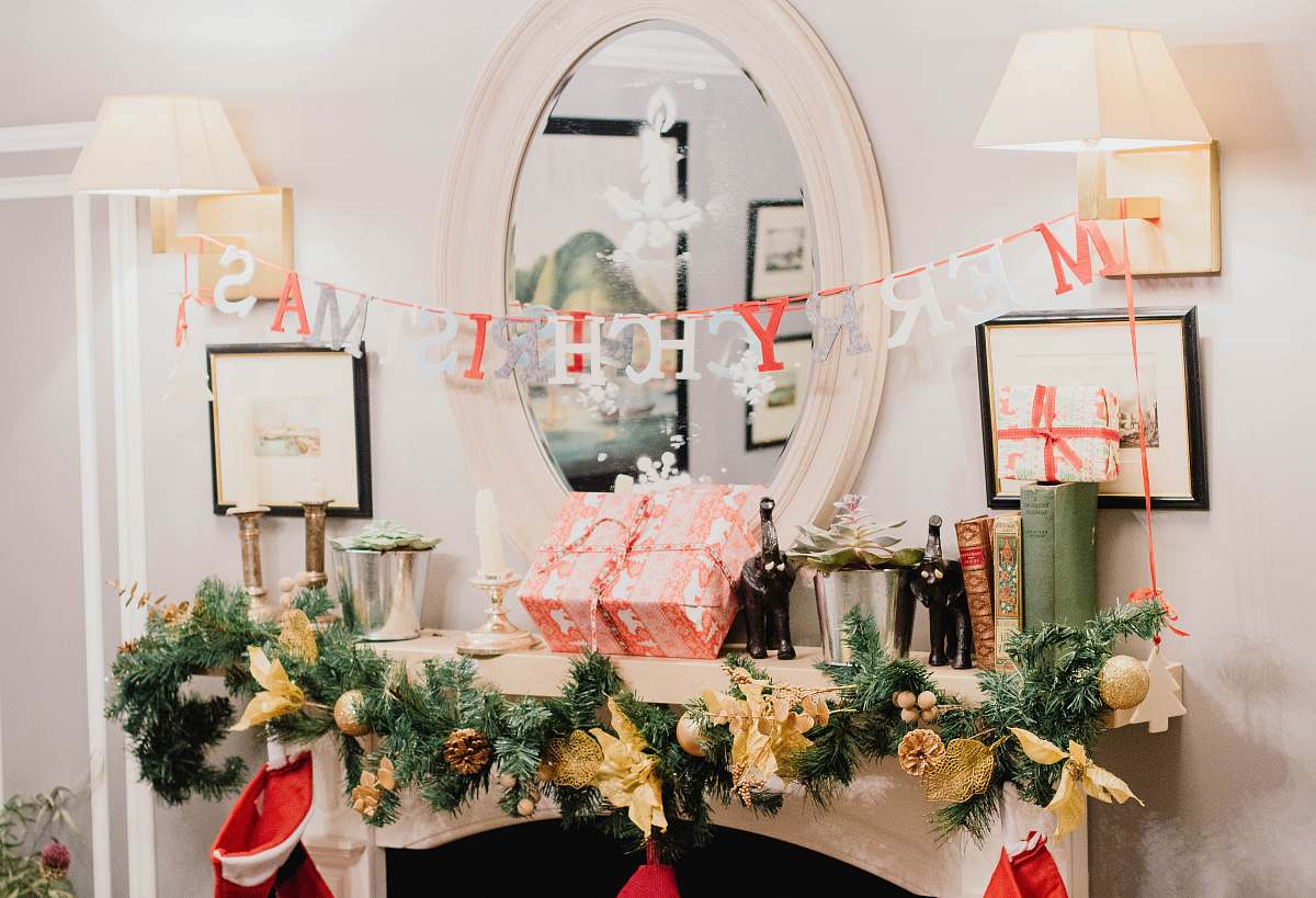 pottery Merry Christmas letter banner hanging on sconces in white painted room potted plant