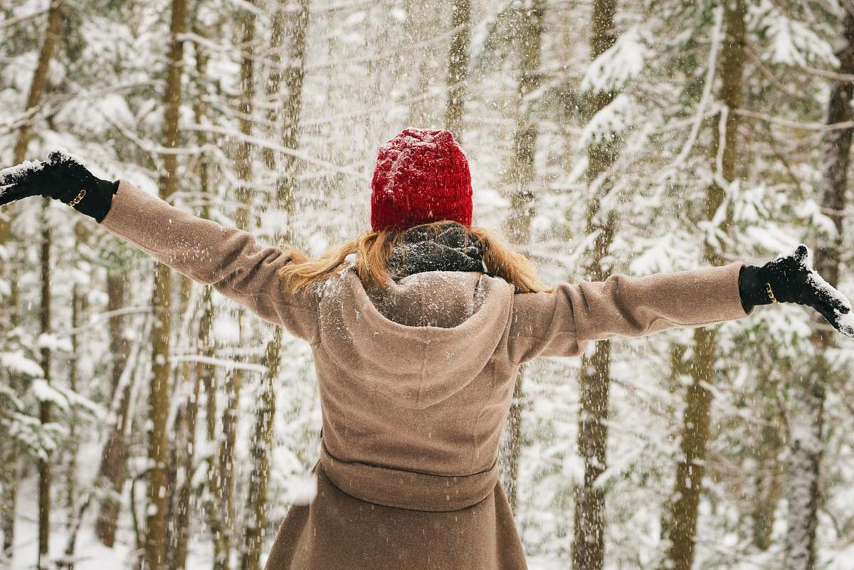 woman woman wearing hoodie spreading her arm near trees with snows lake placid
