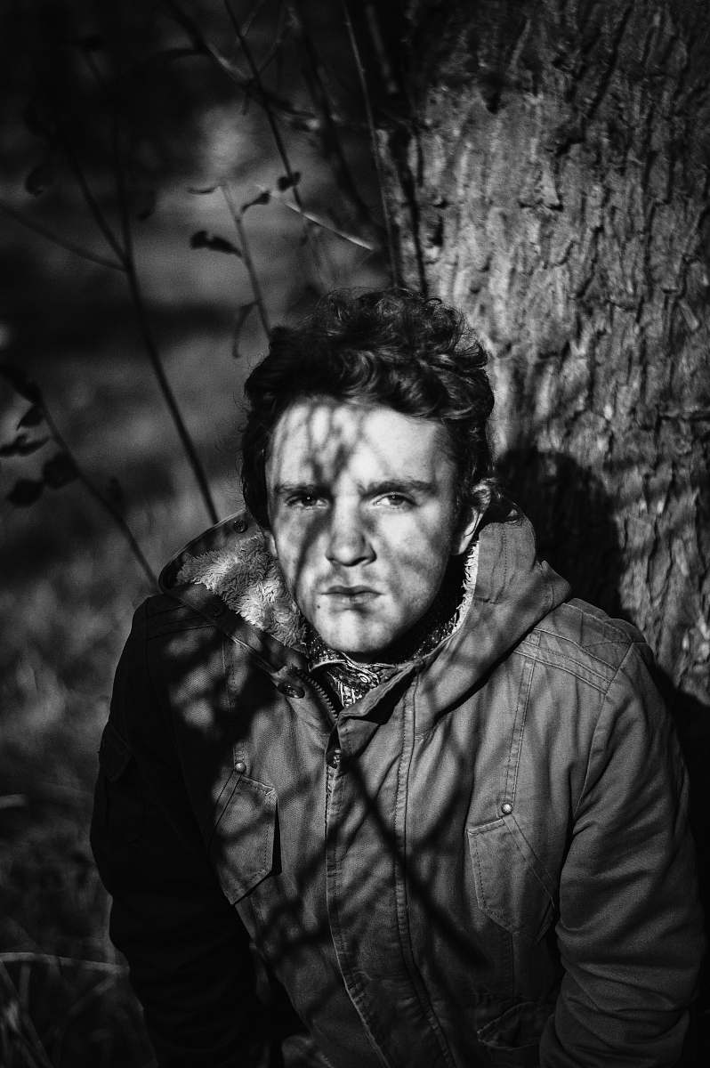 people grayscale photo of man under tree person