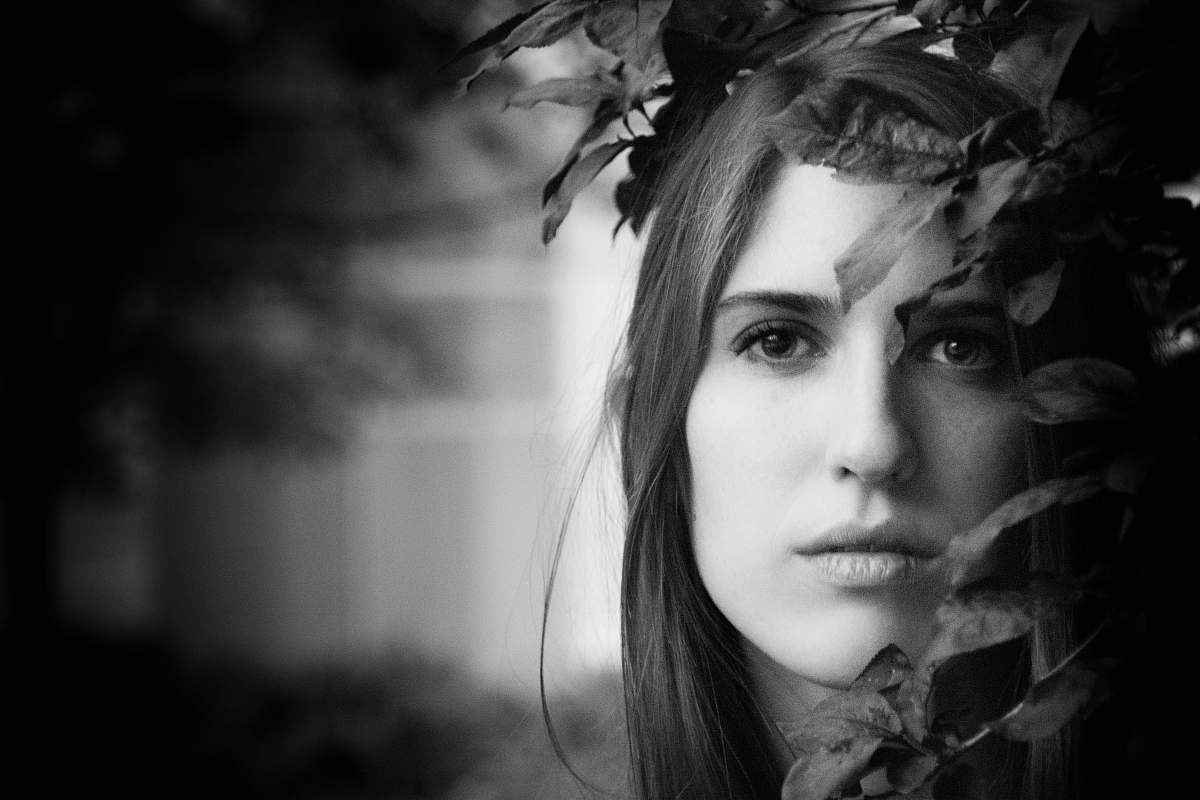 portrait grayscale photo of woman beside leaves female
