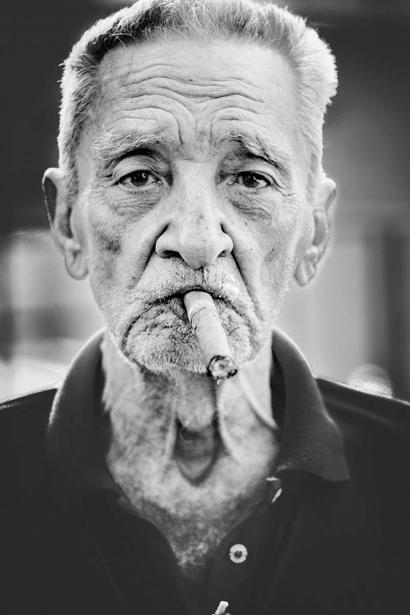 people grayscale photography of man smoking cigar person