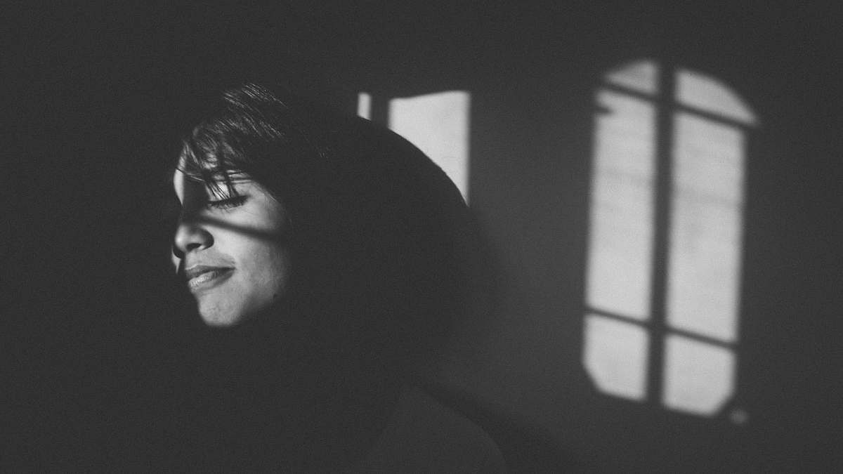 grey grayscale photography of woman leaning on wall with light portrait