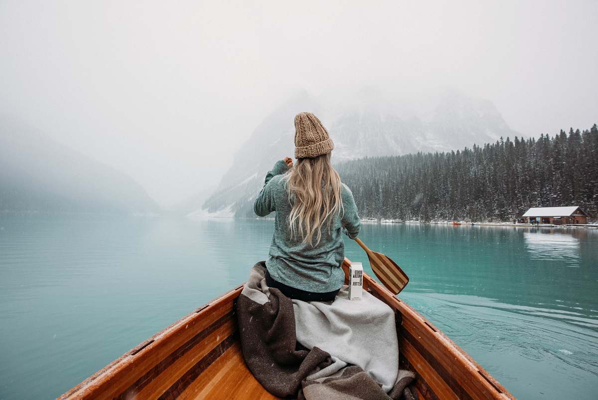 canoe woman in gray hoodie sitting on brown wooden boat on lake during daytime rowboat
