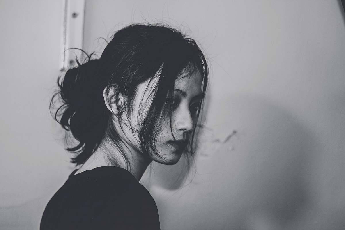 human grayscale photography of woman standing near wall grey