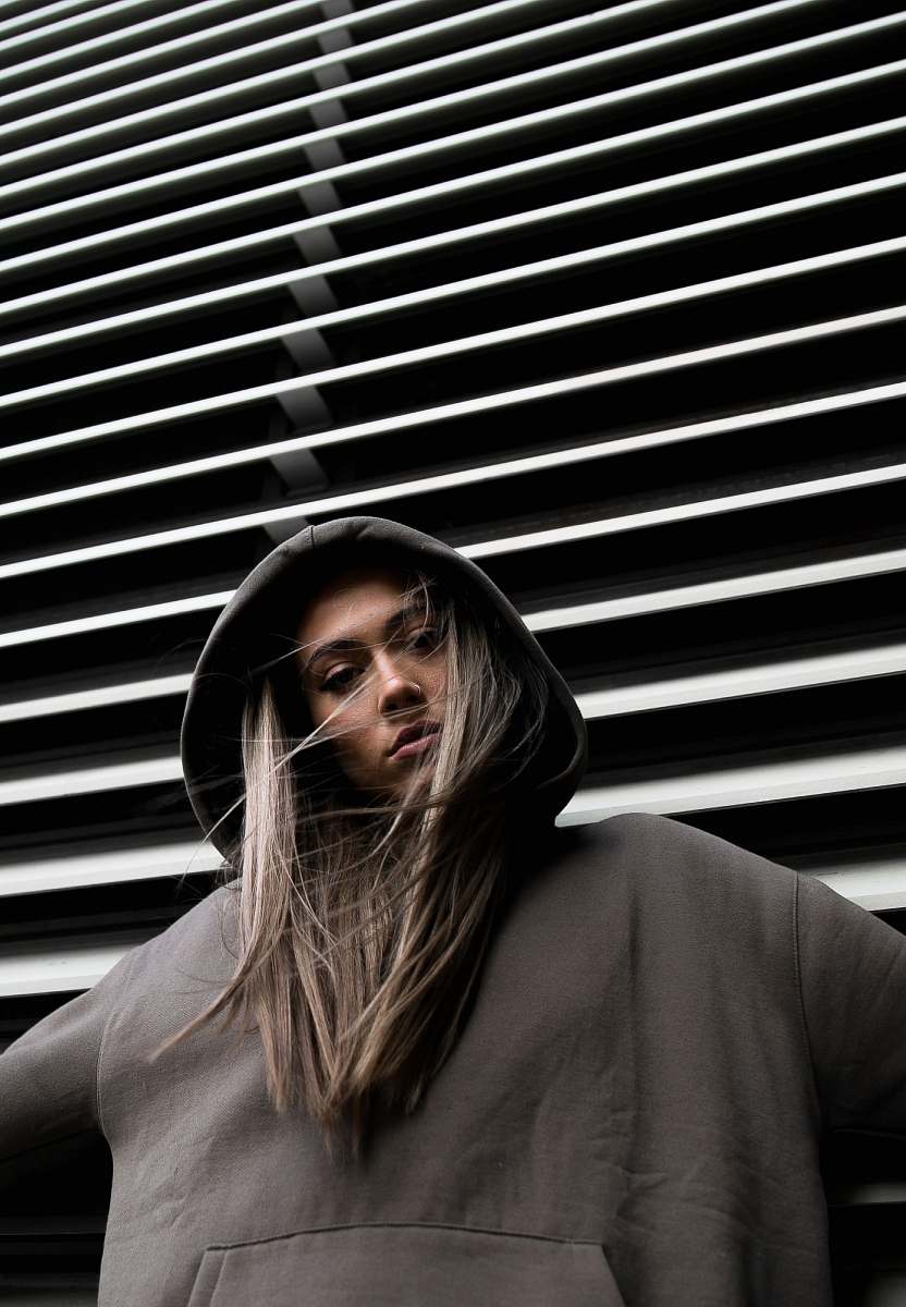 person woman in hoodie standing in front of white wall human
