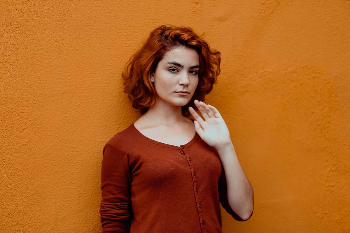 person woman in red button-up shirt leaning orange wall human