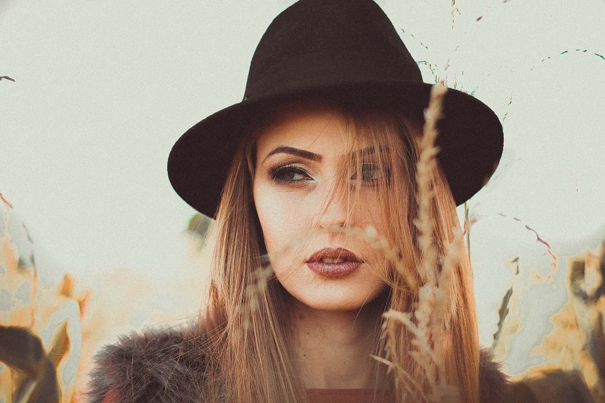 person woman wearing black hat standing beside beige grass hat