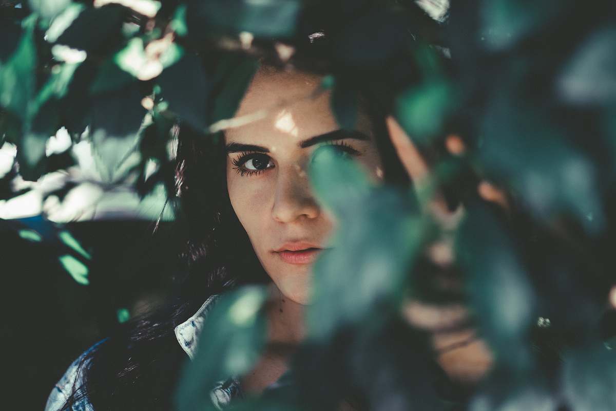 human woman wearing blue denim top hiding beside grasses people