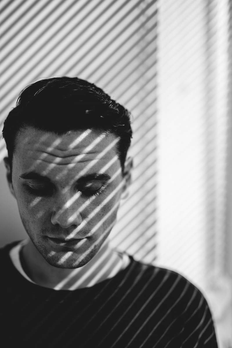 black-and-white man looking down near window in grayscale photography face