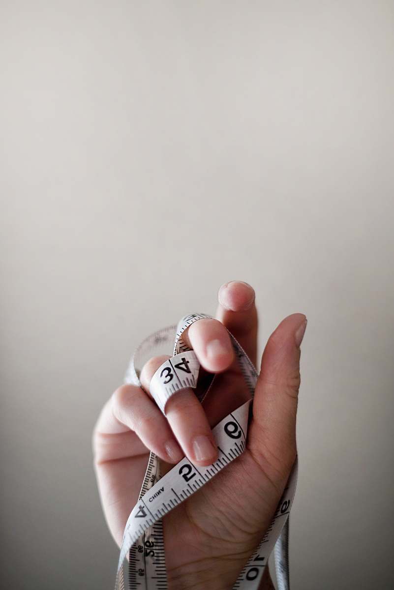 health person's left hand wrapped by tape measure finger