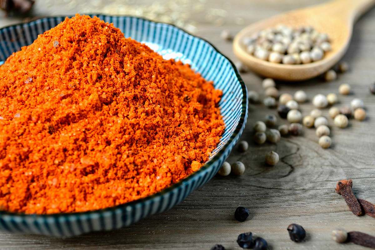 spice red spices on blue bowl with peppers scattered on table spices