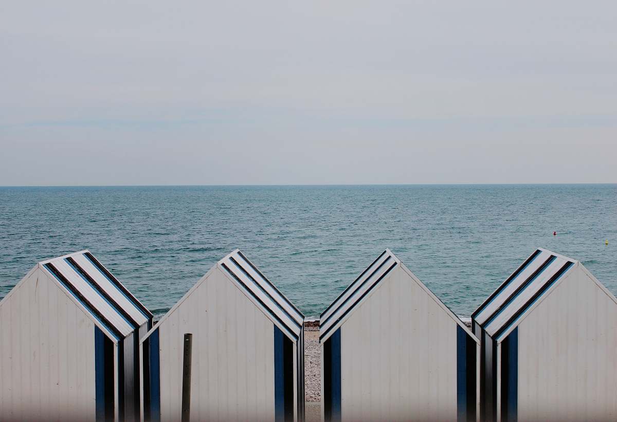 hut four white-and-blue sheds on shoreline grey