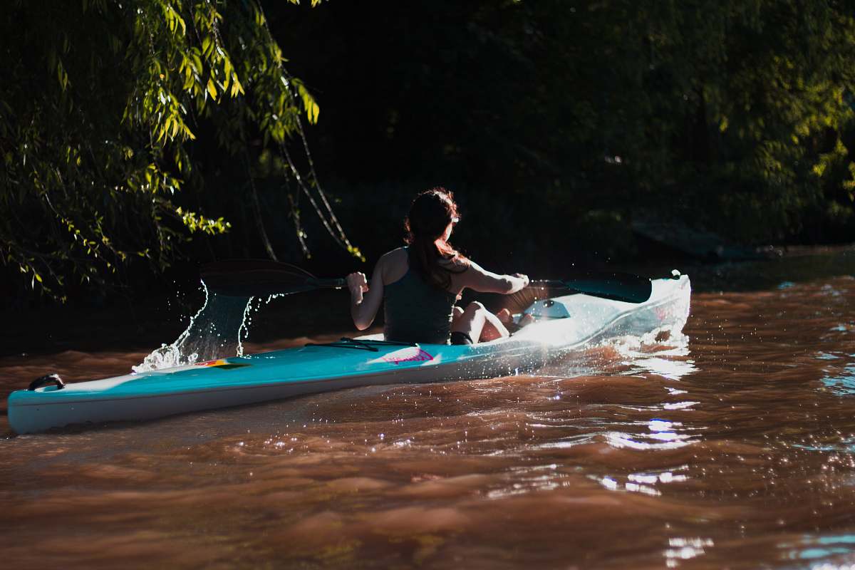 person woman paddling through river boat