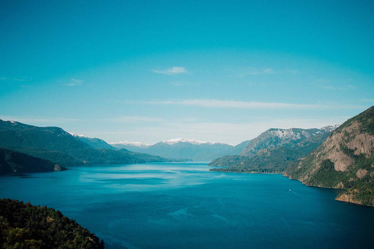 outdoors calm body of water surround with mountain during daytime land