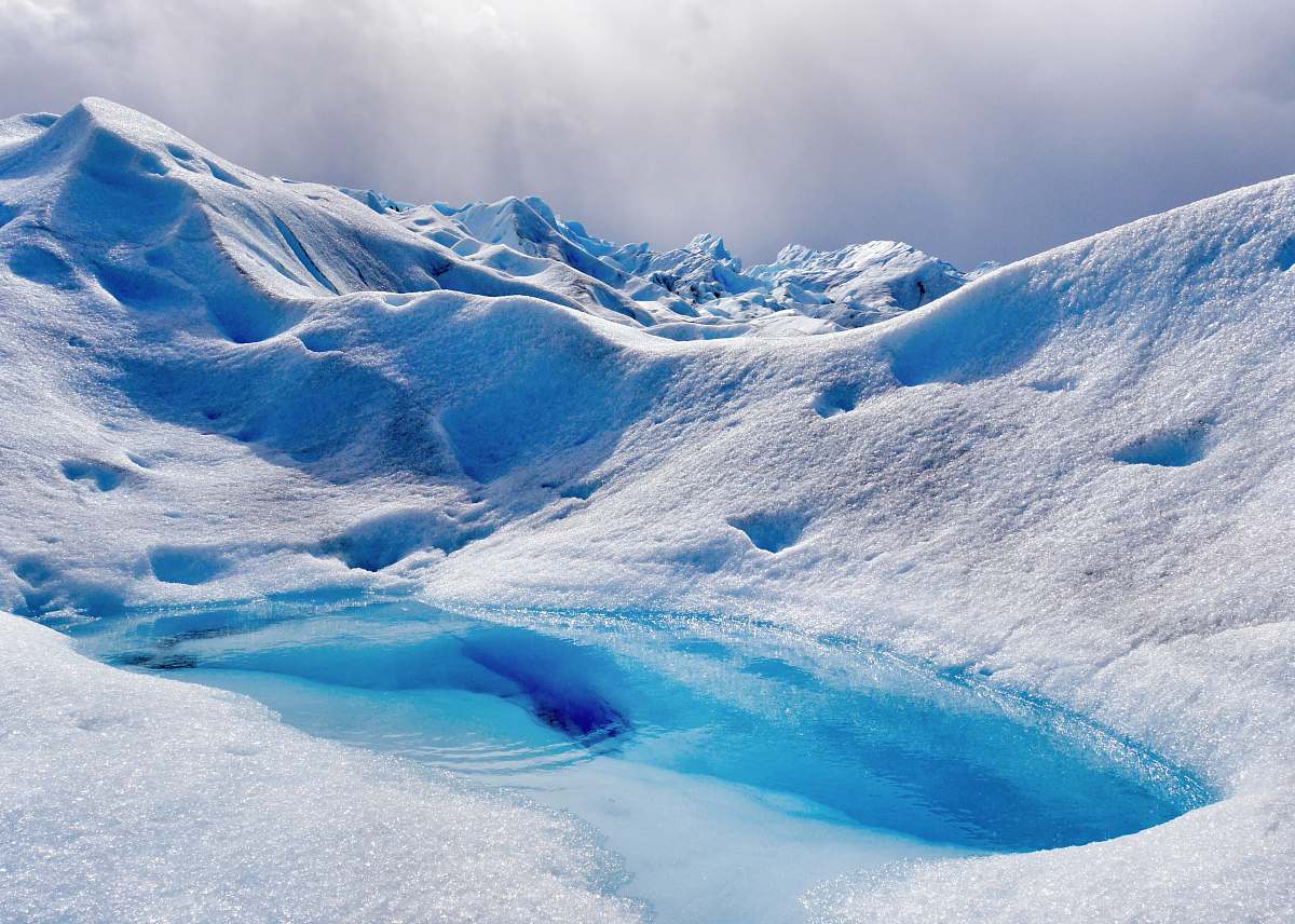 glacier lake in the middle of ice-covered mountain during daytime snow