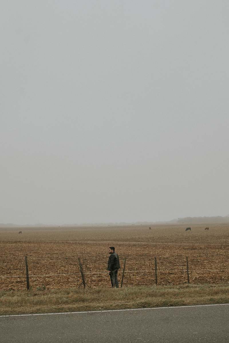 person man wearing black jacket standing on brown field human