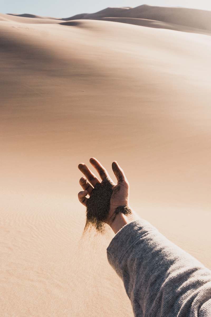 desert person dropping sand from his hand during daytinme hand