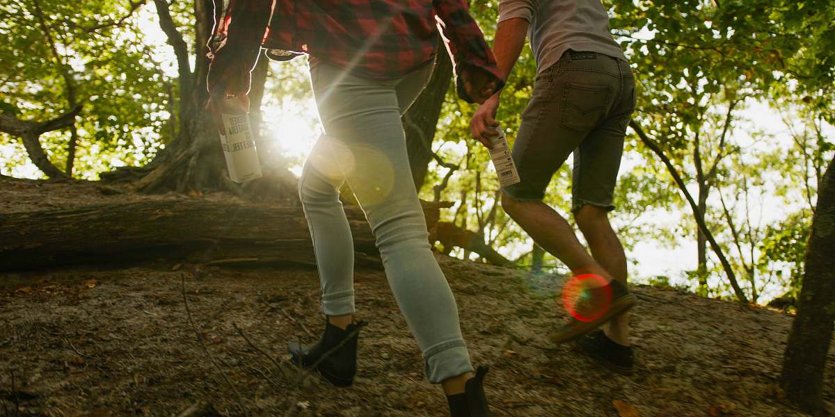 human A man and woman walking in a forest holding a Boxed Water carton flare