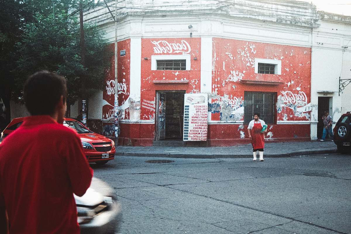 human man in red apron standing beside Coca-Cola building car