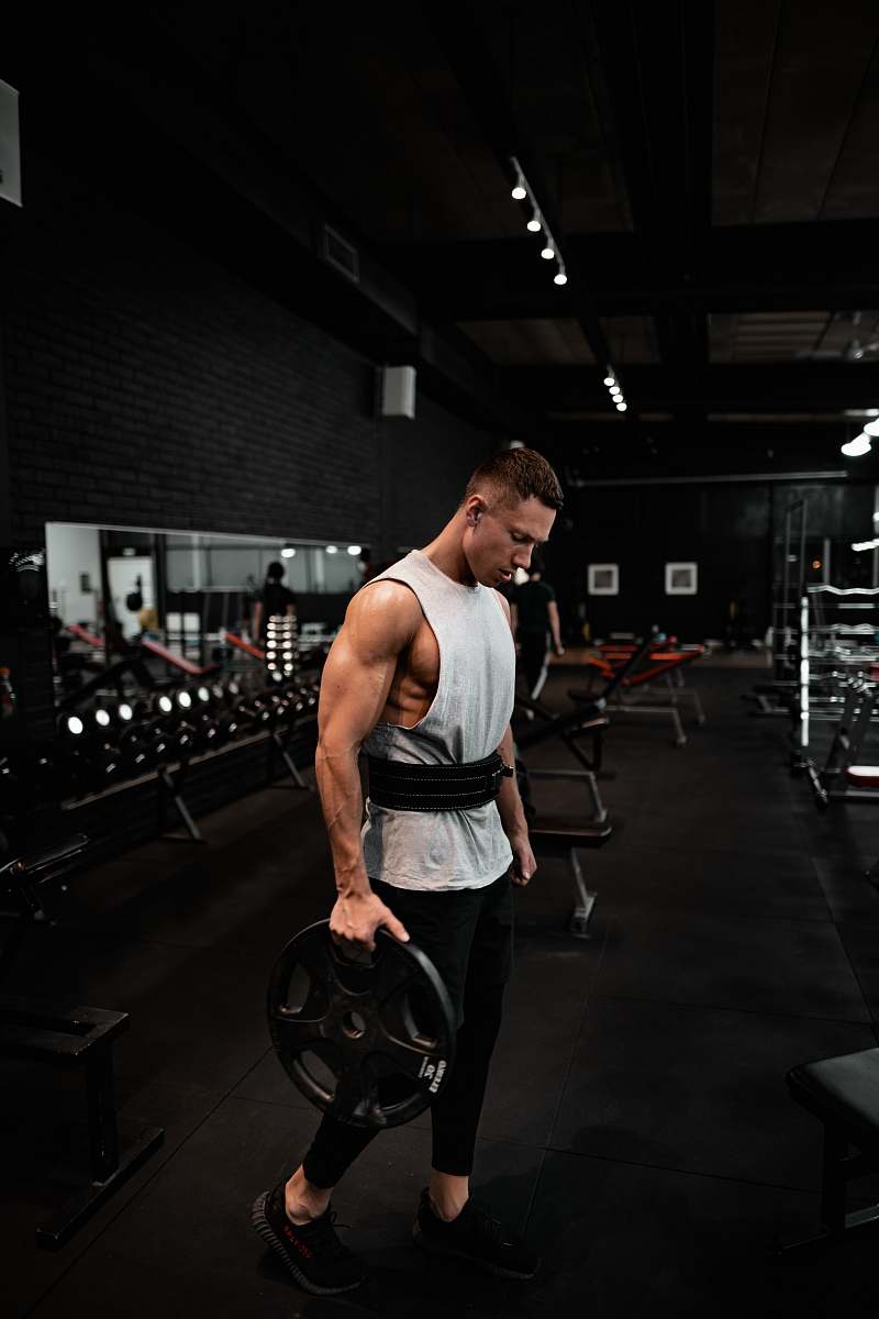 human man in white tank top holding bumper plate fitness