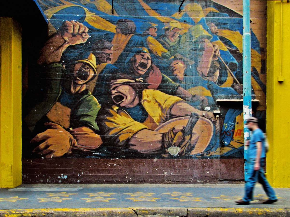 human man walking beside graffiti artwork graffiti