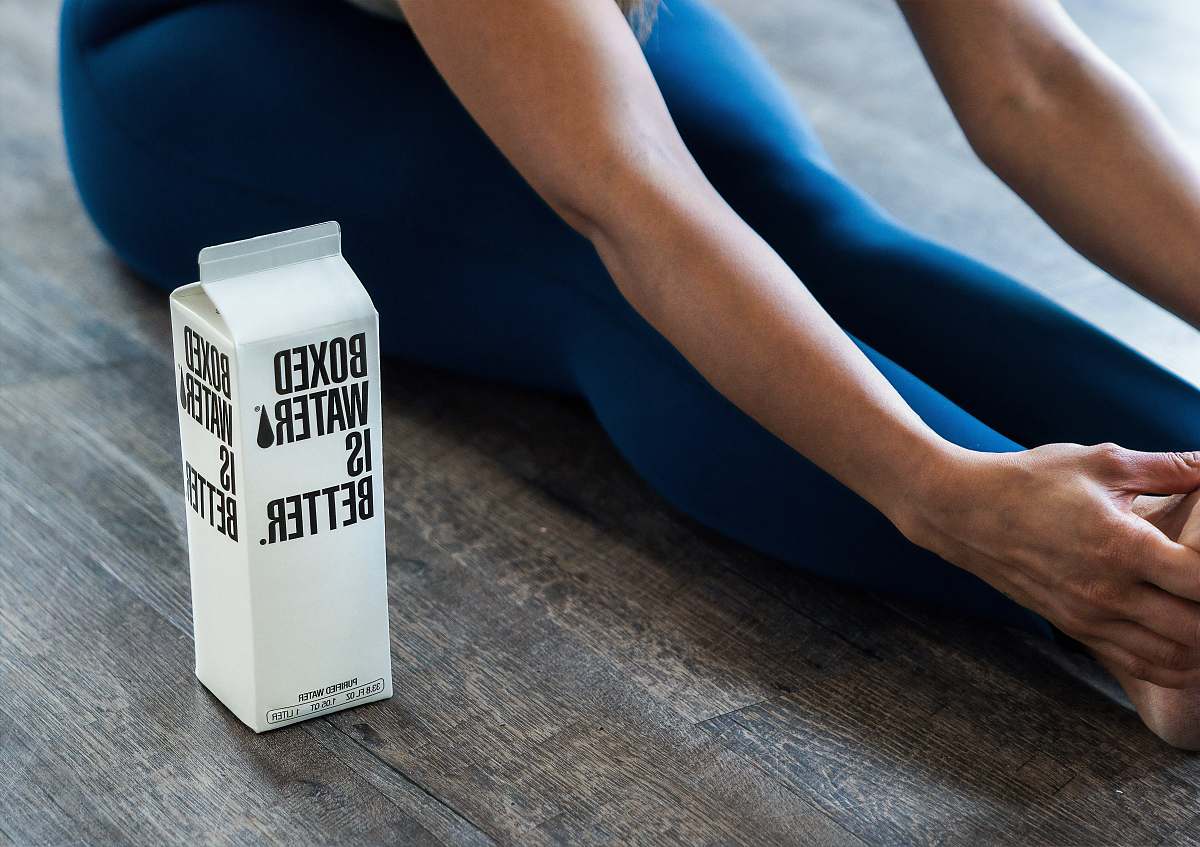human person wearing blue leggings sitting near boxed water apparel