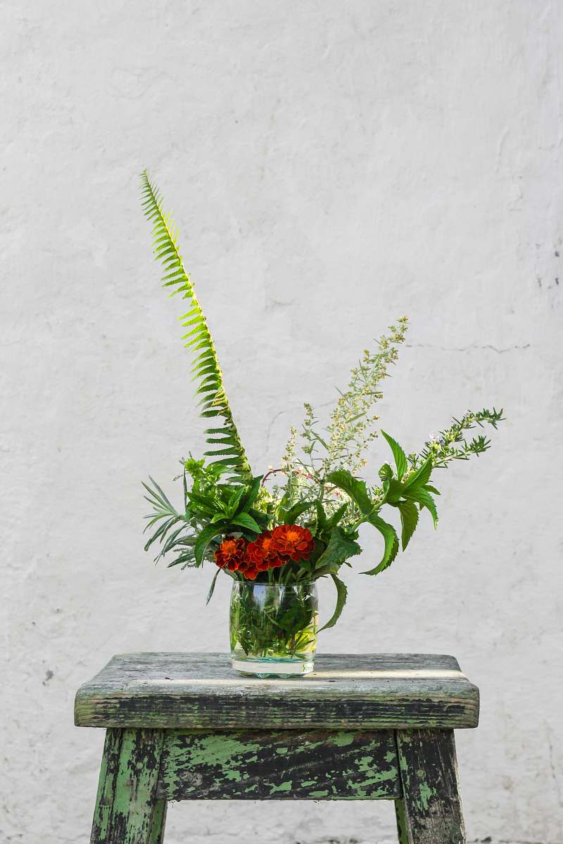 flower red petaled flowers in glass vase on blue wooden bar stool vase