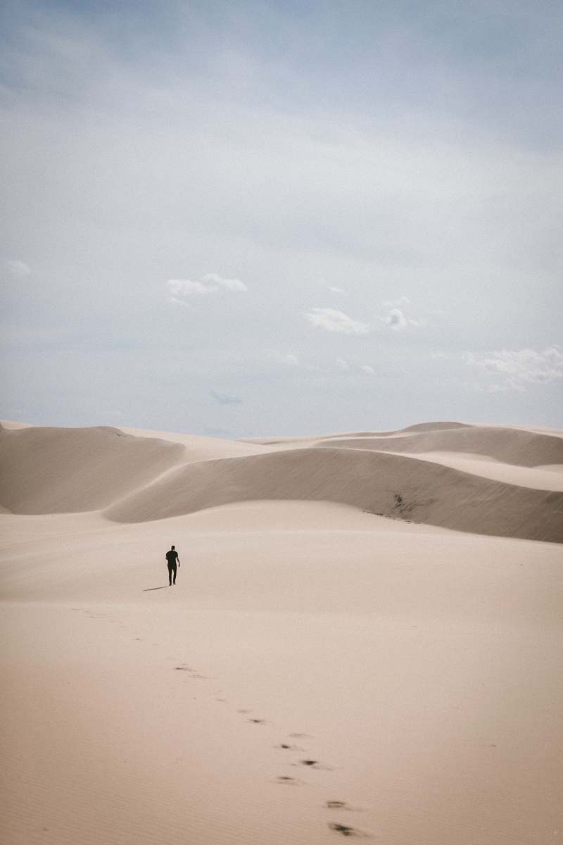 grey person waling on desert dune