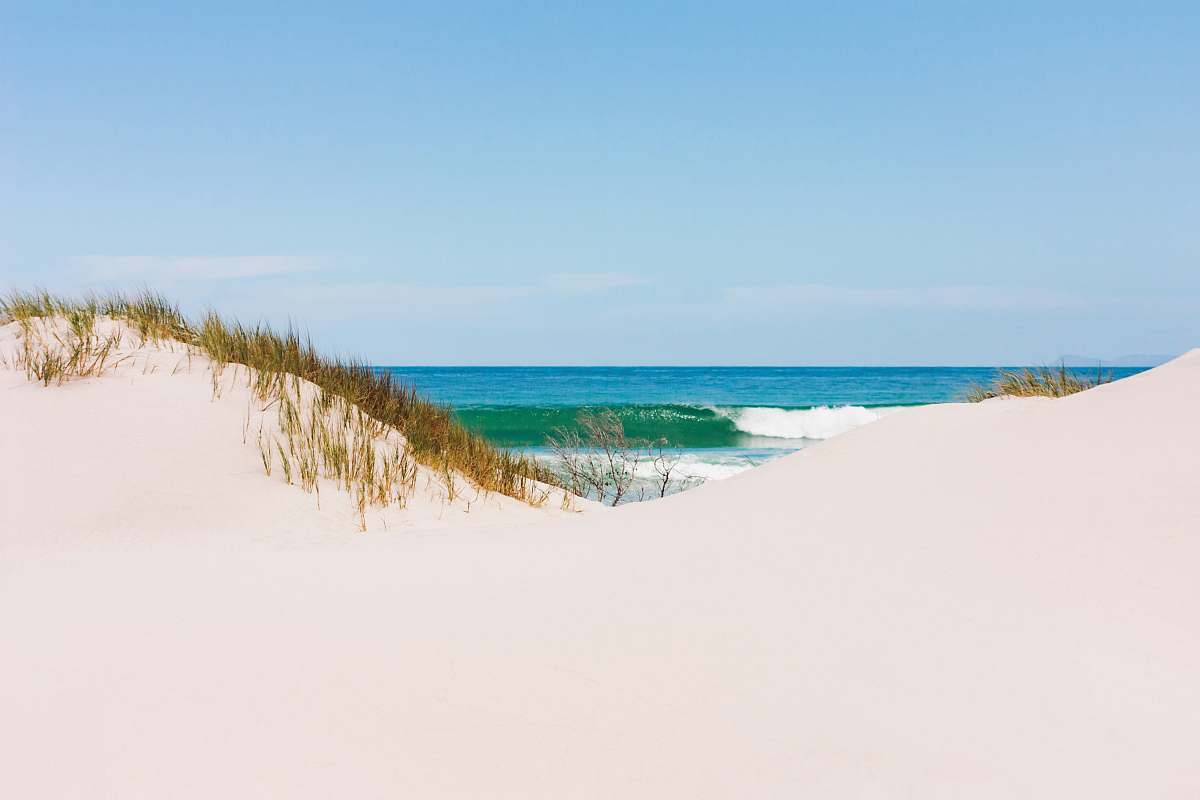 sand white sand near shore under clear sky at daytime outdoors