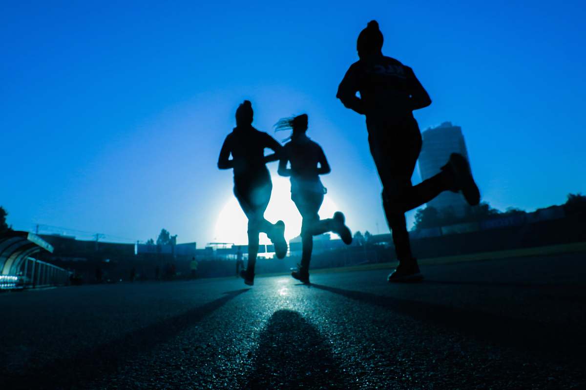 person silhouette of three women running on grey concrete road human