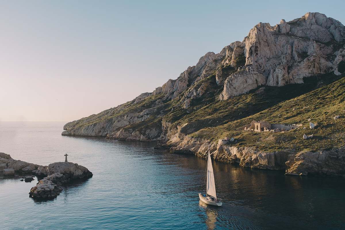 cliff white sailboat near island rocks coast
