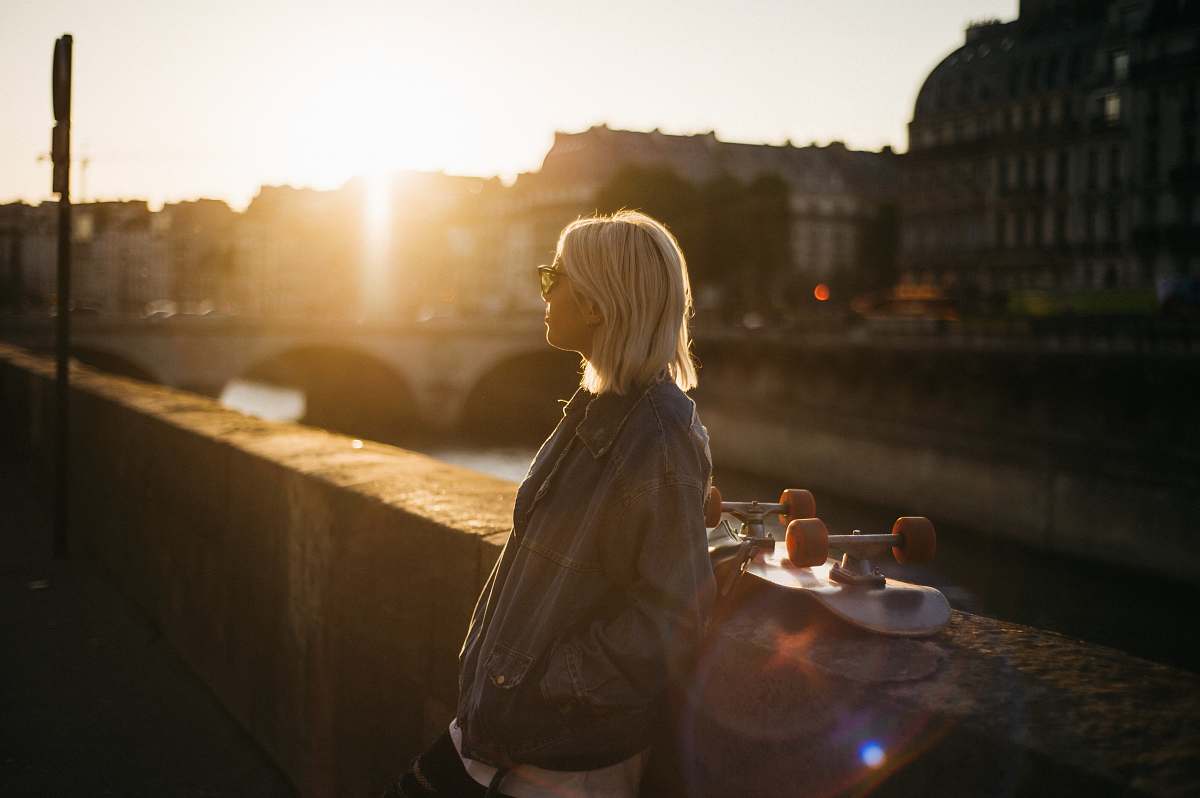 blonde woman leaning on concrete wall near skateboard female